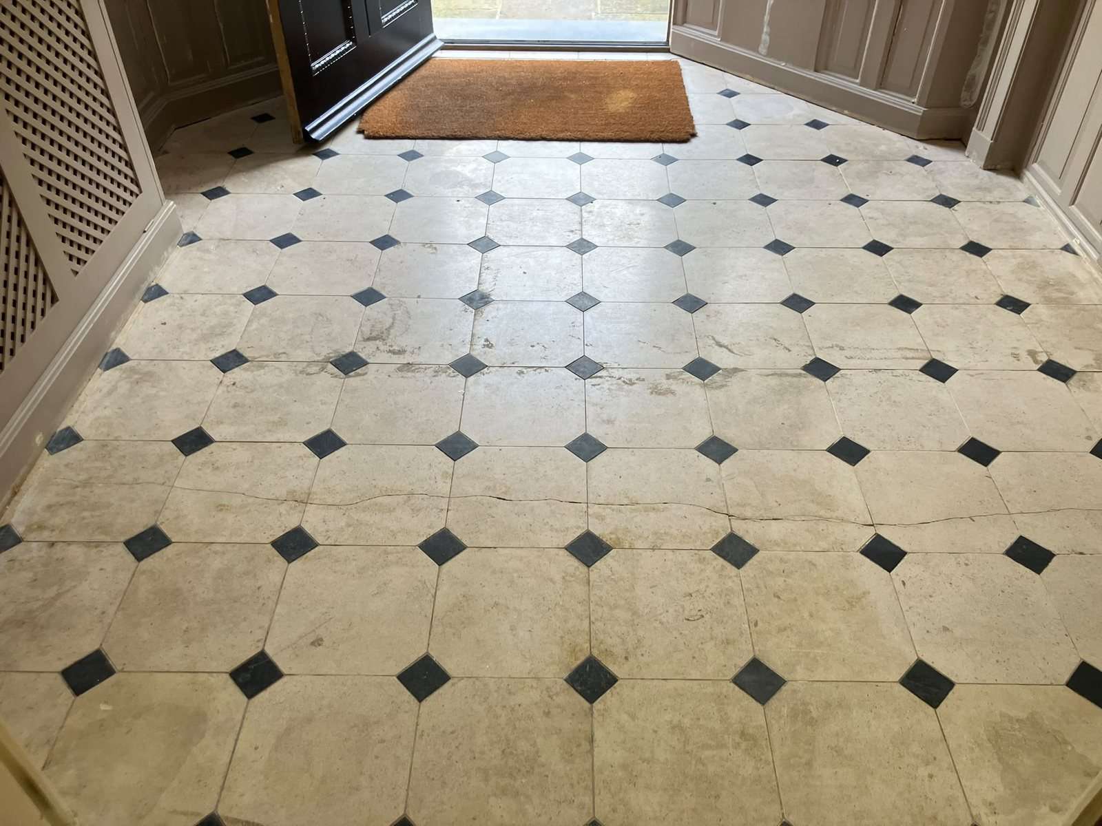 Limestone entrance hall after the carpet was lifted, stained and dirty with a crack running across the floor
