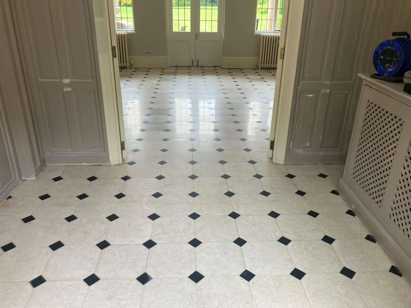 Restored limestone floor with black insets running from the entrance hall into the main room