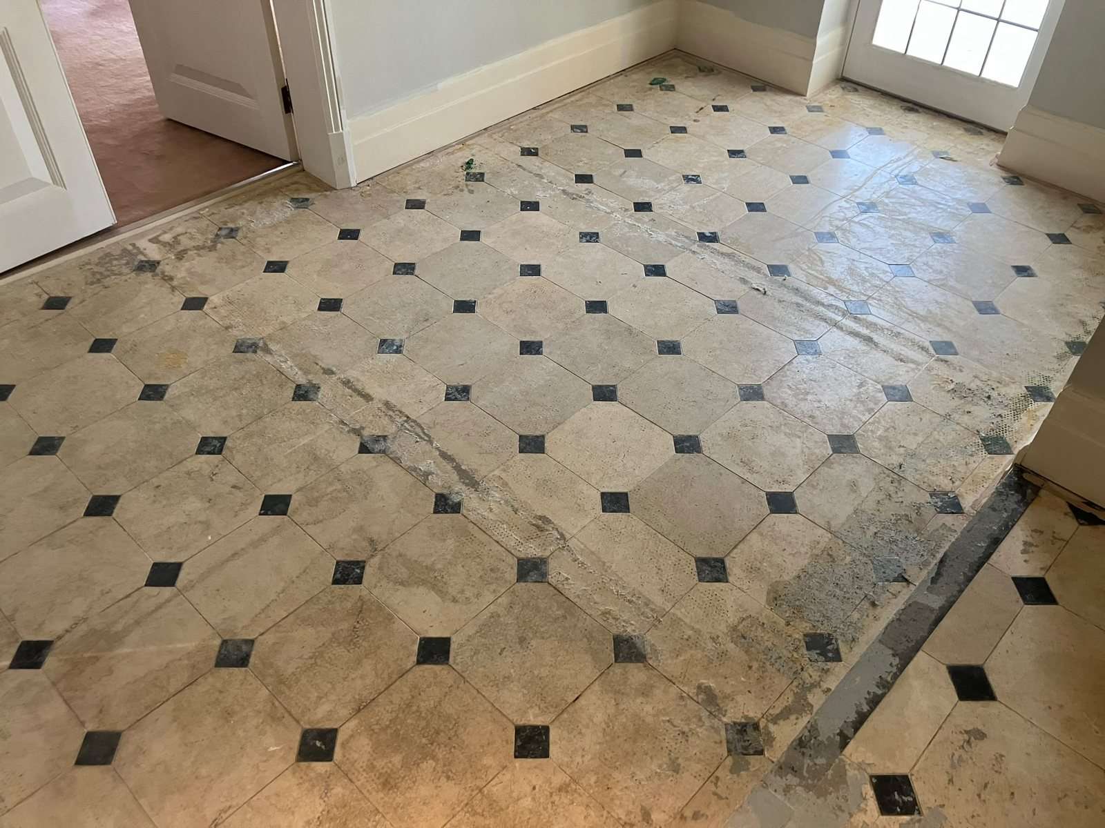 Limestone garden room floor before restoration, with glue, residue and dark staining