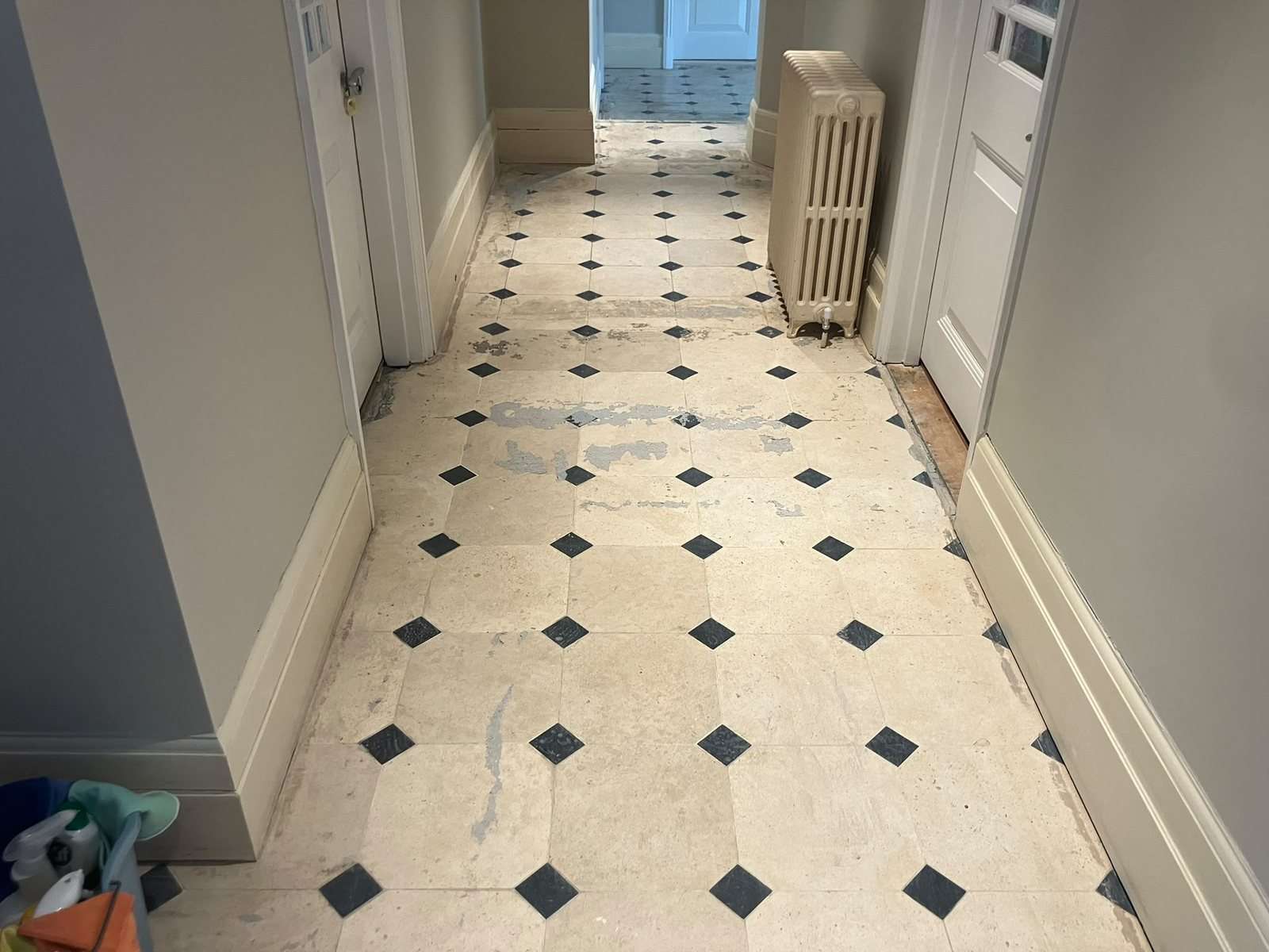 Limestone hallway floor with black inset squares, covered in old carpet glue and grey residue