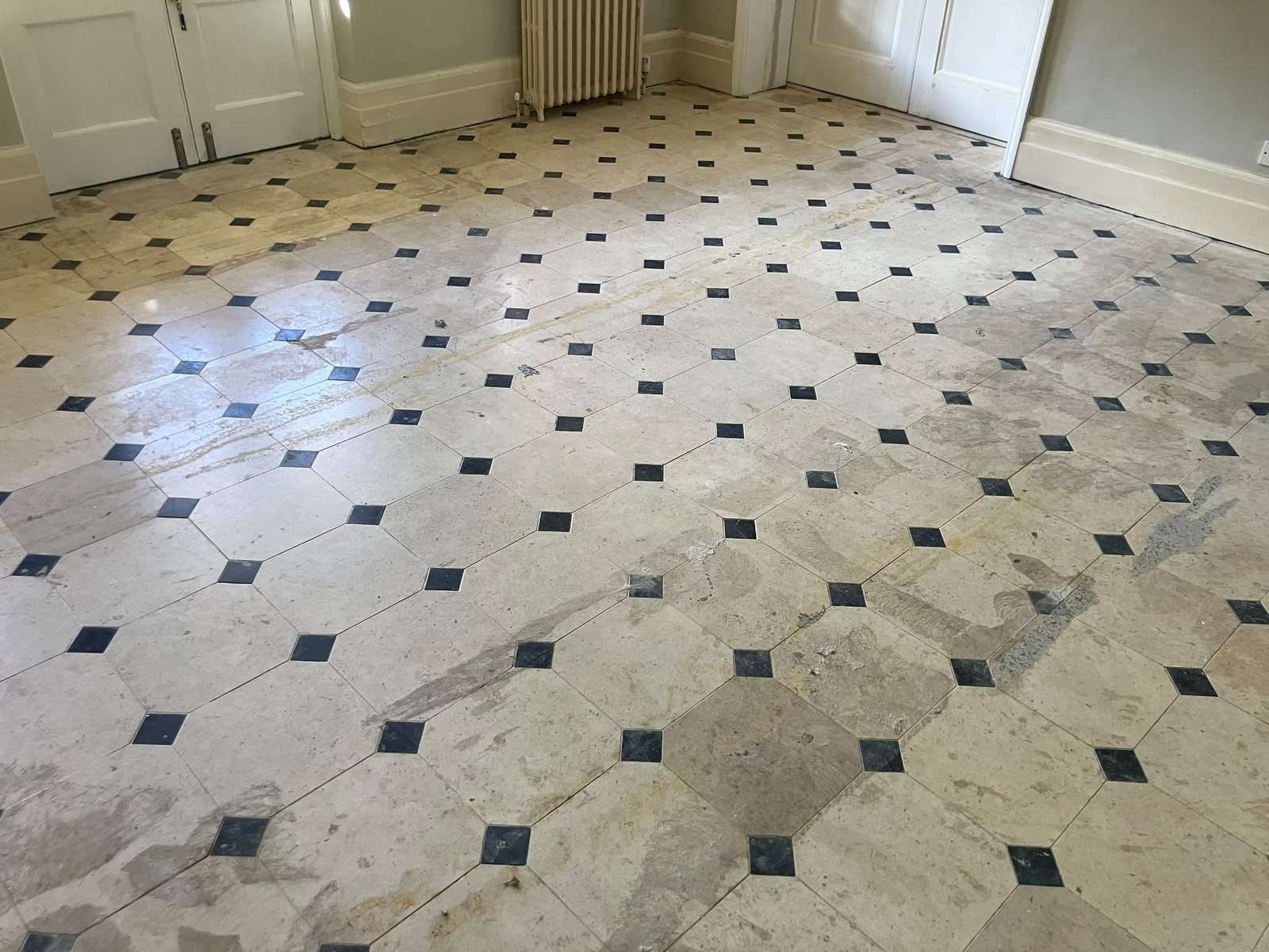 Large limestone room after the carpet was lifted, with glue residue, staining and patches
